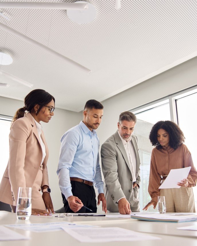 Finance professionals reviewing business reports and documents together in an office.